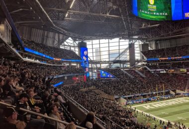 Tribunes pleines et pelouse du Mercedes-Benz Stadium, sous son toit et ses écrans géants, des spectateurs levant la lumière de leur téléphone