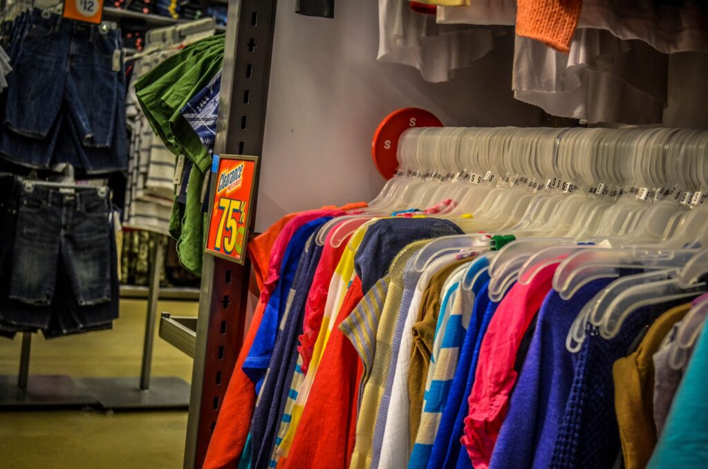 Portant de vêtements d'été colorés en liquidation dans un magasin Old Navy, avec une étiquette jaune et rouge annonçant des prix à 75 cents