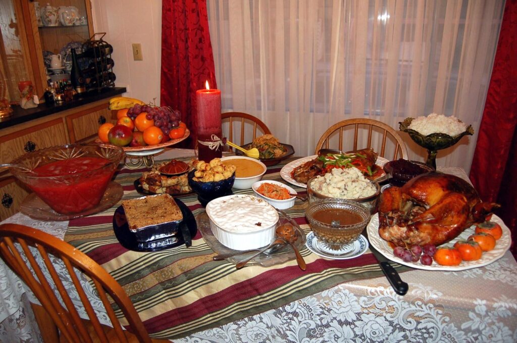 Table de fête garnie d'une dinde rôtie, de sauce aux canneberges, de purée, de haricots verts et de desserts