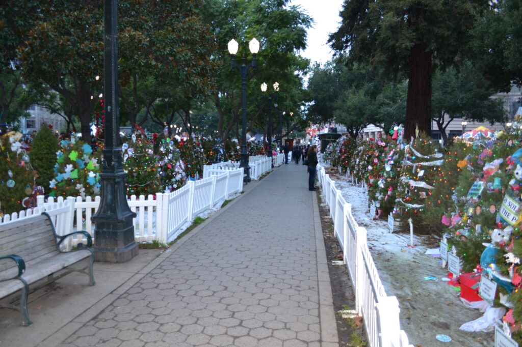 Allée bordée de petits sapins décorés derrière des barrières blanches, à Christmas in the Park, sur la Plaza de César Chávez à San José