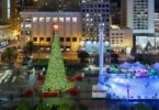 Union Square de nuit, vue d'en haut, avec le grand sapin illuminé surmonté d'une étoile rouge et la patinoire éclairée en bleu, entre les grands magasins