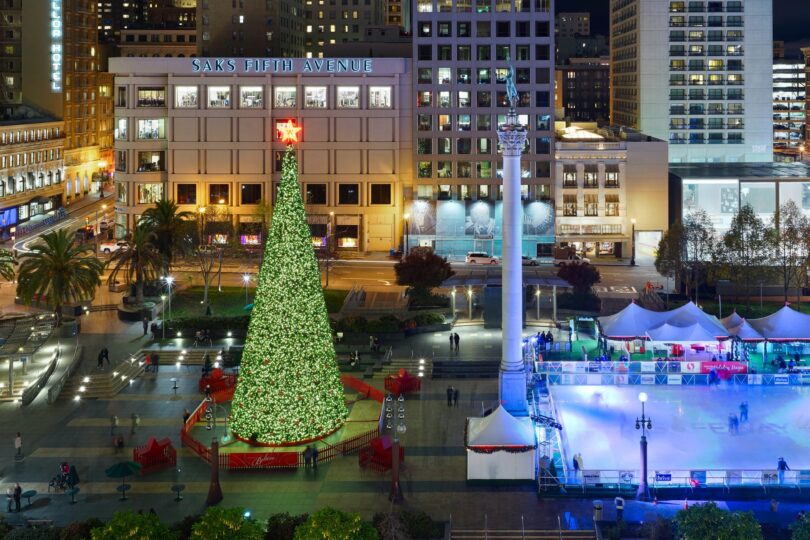 Union Square de nuit, vue d'en haut, avec le grand sapin illuminé surmonté d'une étoile rouge et la patinoire éclairée en bleu, entre les grands magasins