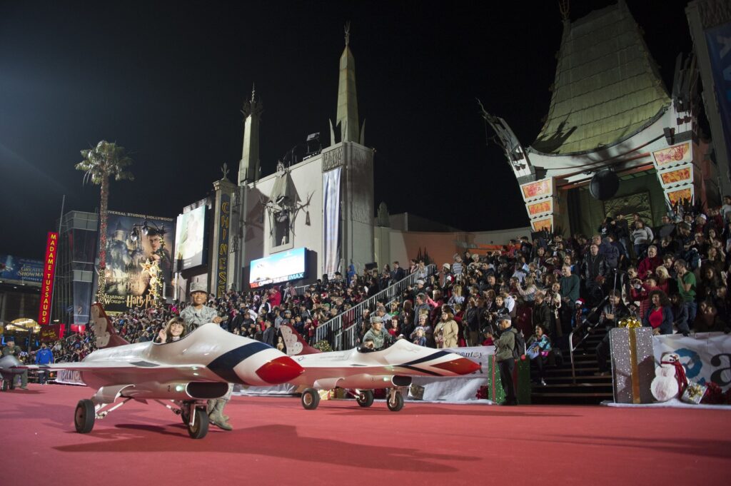 Mini-avions de chasse sur le tapis rouge de la Hollywood Christmas Parade, devant les tribunes pleines et le TCL Chinese Theatre, de nuit