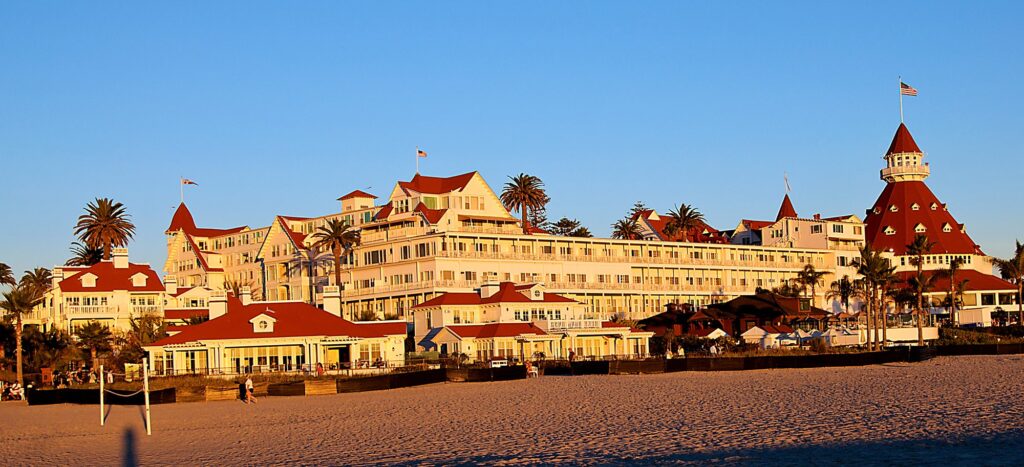Le Hotel del Coronado, grand hôtel victorien aux toits rouges, au soleil couchant, vu depuis la plage