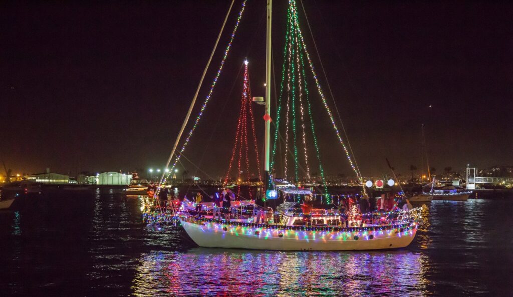 Voilier dont les mâts et la coque sont couverts de guirlandes lumineuses, de nuit, sur la baie de San Diego