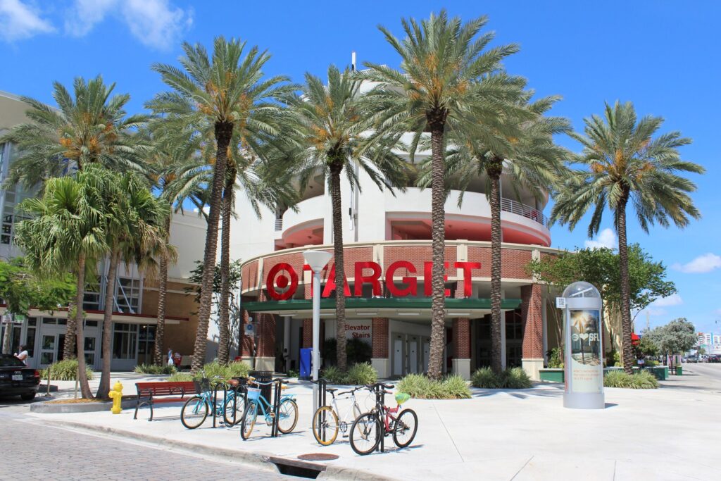 Façade arrondie d'un magasin Target à l'enseigne rouge, entourée de grands palmiers, avec des vélos garés sur le trottoir, sous un ciel bleu