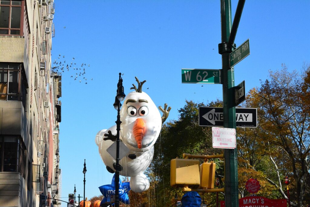 Le ballon géant du bonhomme de neige Olaf entre les immeubles de Central Park West, sous les panneaux de la 62e rue