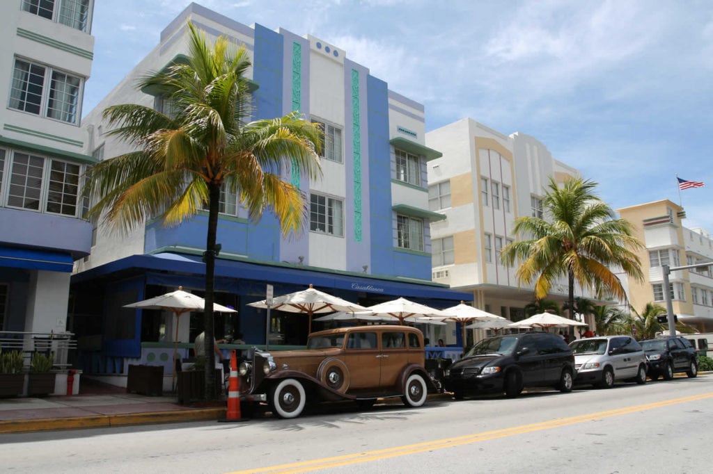 Hôtels Art déco aux façades pastel le long d'Ocean Drive, à South Beach, avec palmiers et voitures garées