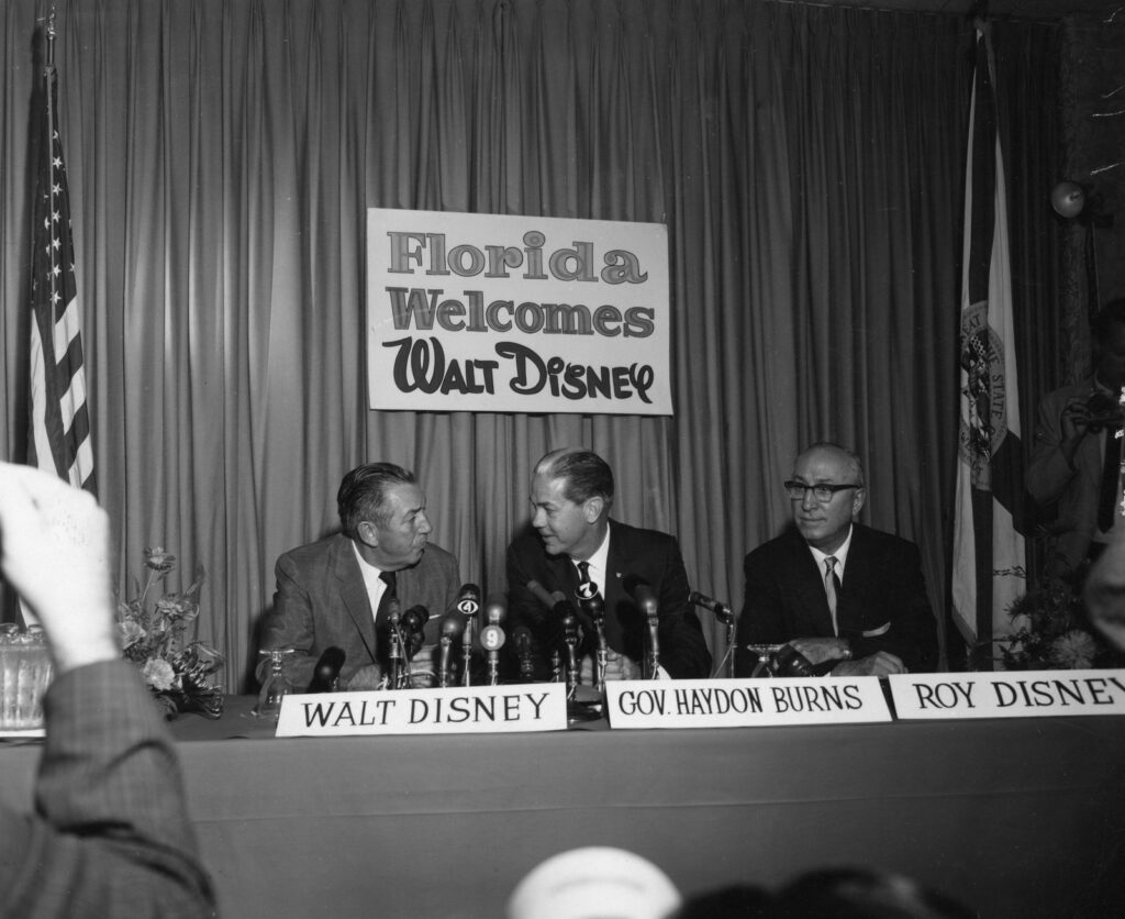 Walt Disney, le gouverneur de Floride Haydon Burns et Roy Disney devant une carte du projet, lors d’une conférence de presse à Orlando en 1965
