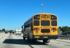 Bus scolaire jaune vu de l'arrière, avec l'inscription School Bus et Stop when red lights flash, sur une autoroute de Floride sous un ciel bleu