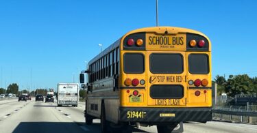 Bus scolaire jaune vu de l'arrière, avec l'inscription School Bus et Stop when red lights flash, sur une autoroute de Floride sous un ciel bleu