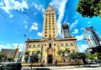 La Freedom Tower, tour ocre de style néo-espagnol du Miami Dade College, sous un ciel bleu, entre les gratte-ciel du centre de Miami