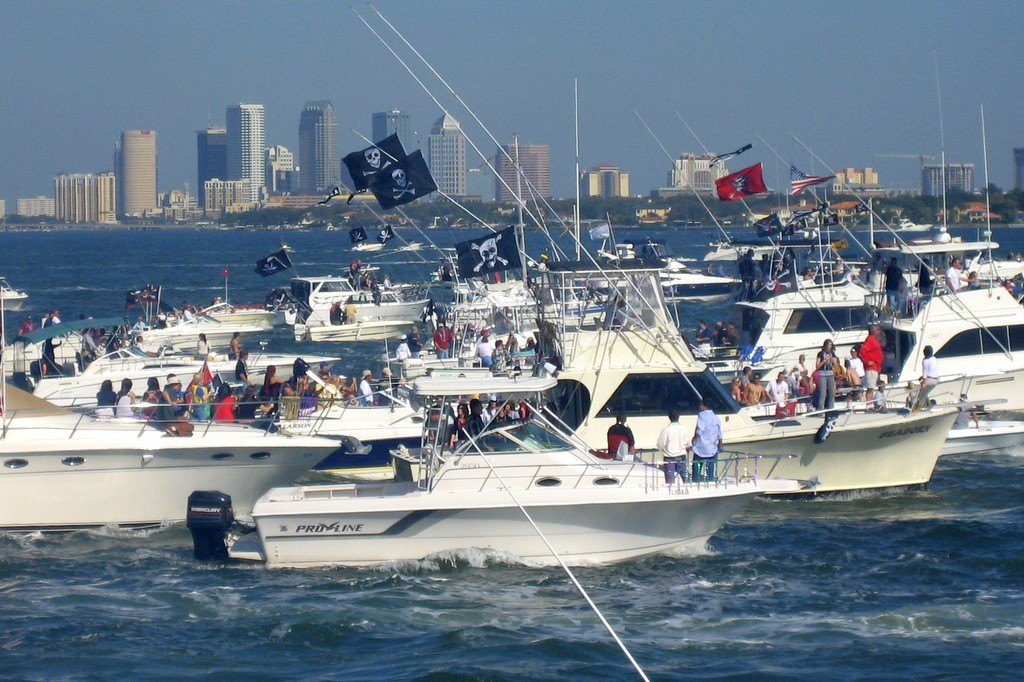 Des dizaines de bateaux de plaisance blancs, certains arborant des drapeaux pirates noirs, naviguent en groupe dans la baie de Hillsborough, les gratte-ciel du centre de Tampa à l'arrière-plan
