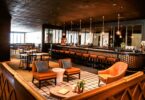 Salle de restaurant-bar avec fauteuils, grand comptoir et suspensions