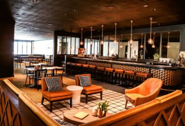 Salle de restaurant-bar avec fauteuils, grand comptoir et suspensions