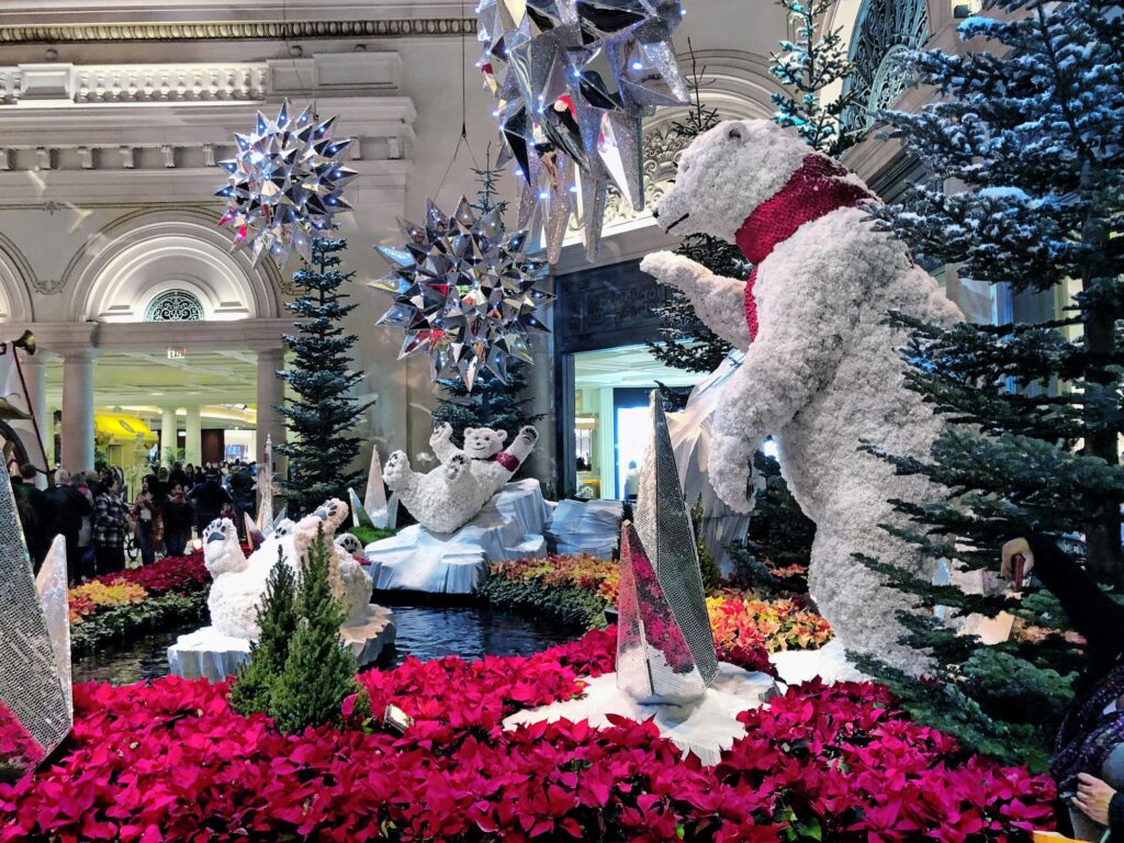 Ours polaires géants, sapins et flocons suspendus dans le décor de Noël du jardin d'hiver du Bellagio, au-dessus d'un tapis de poinsettias rouges