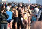 Foule de baigneurs en maillot et de spectateurs en manteau sur la plage de Coney Island le 1er janvier, avant le plongeon