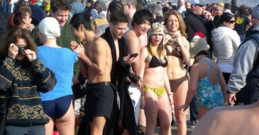 Foule de baigneurs en maillot et de spectateurs en manteau sur la plage de Coney Island le 1er janvier, avant le plongeon