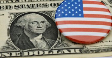 Billet de un dollar à l'effigie de George Washington, sur lequel est posé un badge rond au drapeau américain