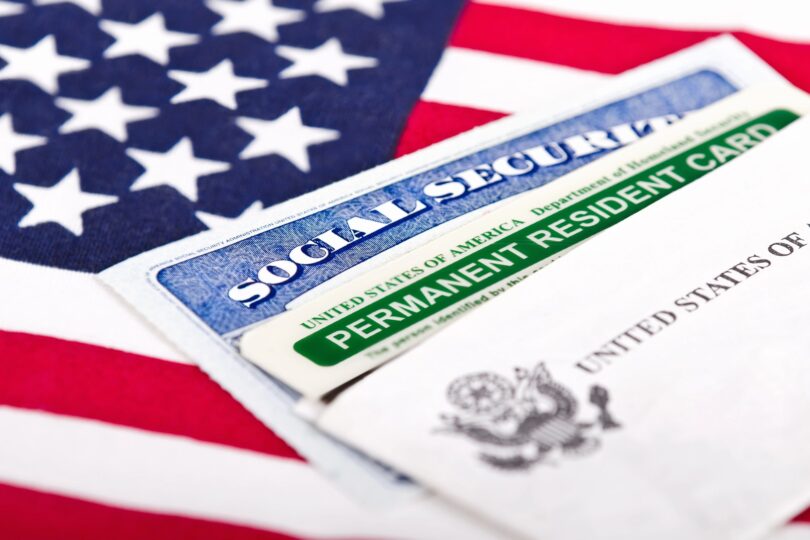 Une carte de résident permanent des États-Unis et une carte de Sécurité sociale posées en éventail sur un drapeau américain