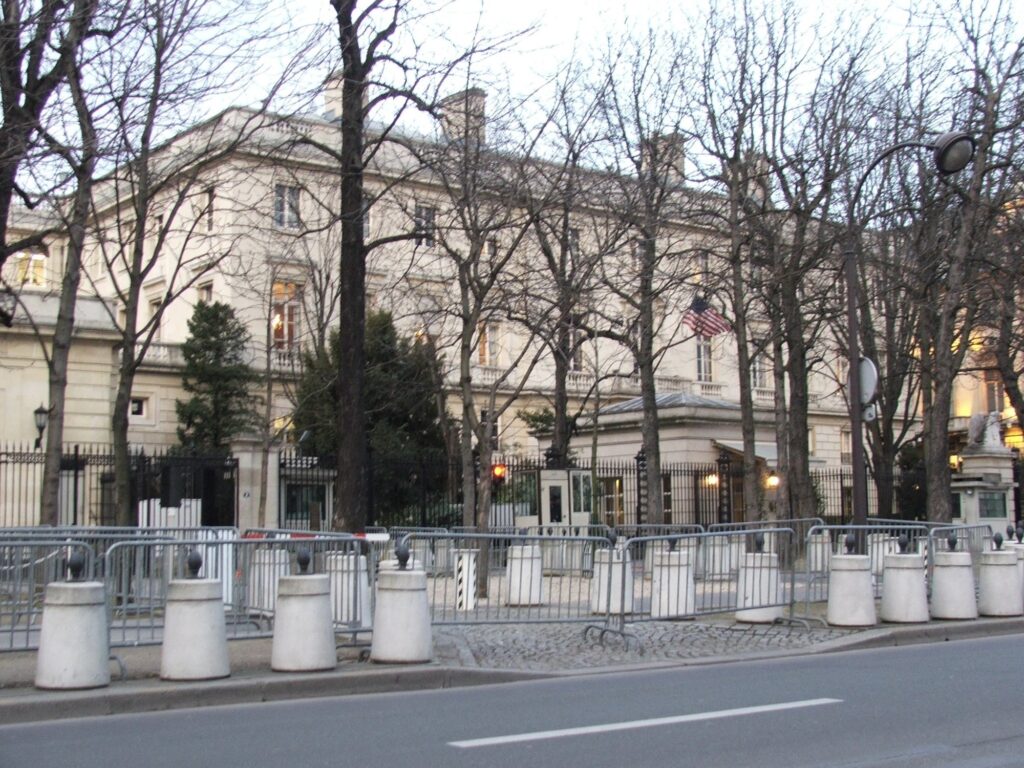 Façade de l'ambassade des États-Unis à Paris, avenue Gabriel, derrière des barrières de sécurité et des arbres