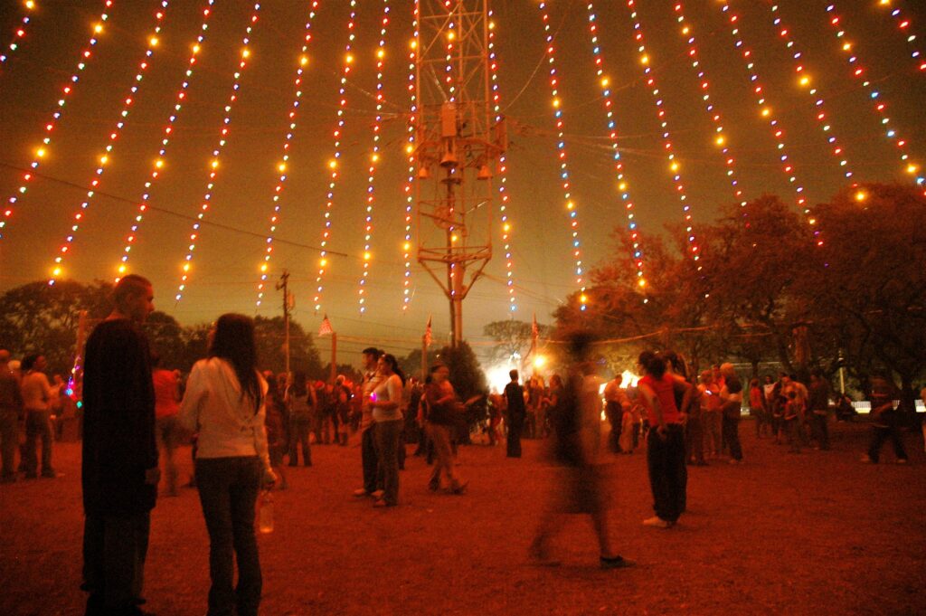 Promeneurs sous le Zilker Tree, des guirlandes de lumières orangées qui descendent en cône d'un pylône, dans Zilker Park à Austin
