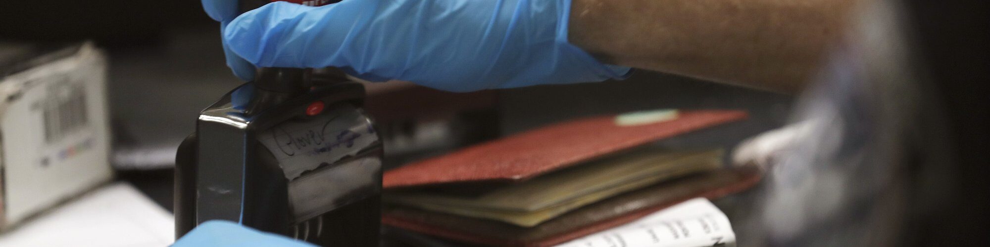 Mains gantées d'un agent des douanes américaines qui tamponne un passeport à son guichet
