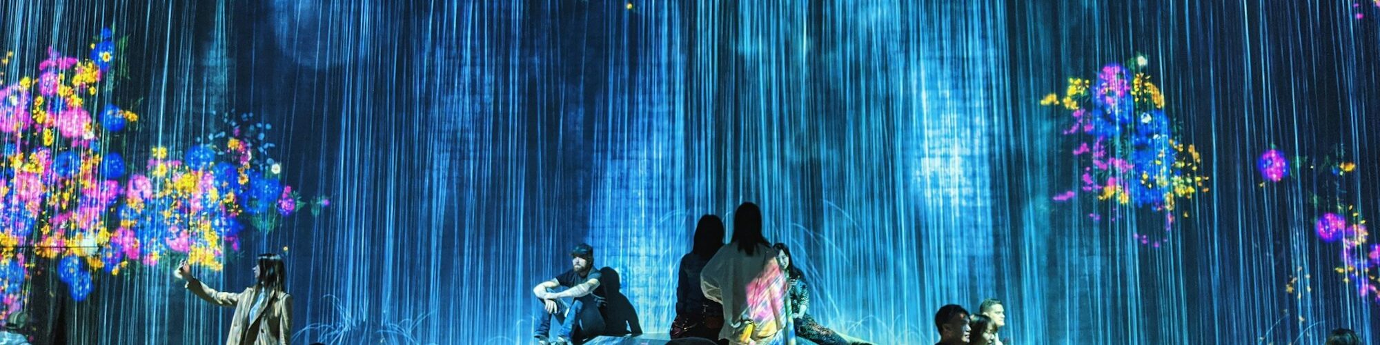 Visiteurs dans une salle d'art numérique immersif, projections du sol aux murs