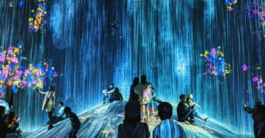 Visiteurs dans une salle d'art numérique immersif, projections du sol aux murs