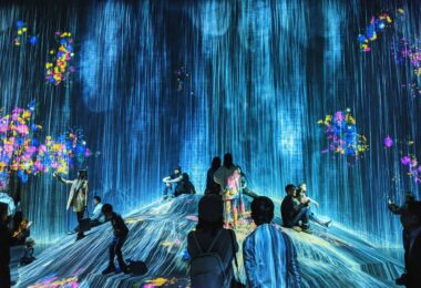 Visiteurs dans une salle d'art numérique immersif, projections du sol aux murs