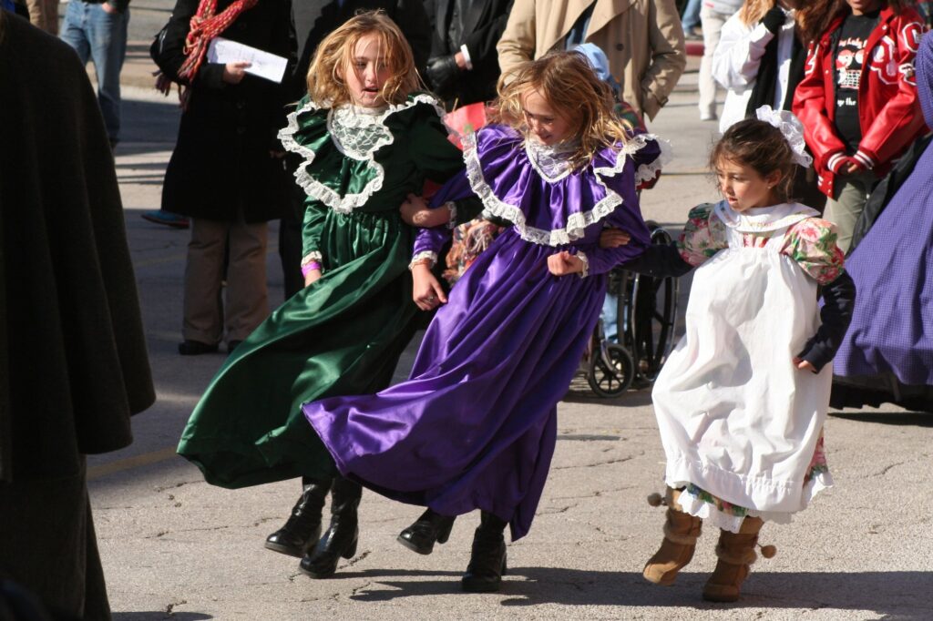 Fillettes en robes victoriennes qui dansent dans la rue pendant Dickens on the Strand, à Galveston