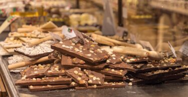 Tablettes de chocolat au lait et noir garnies de noisettes et de fruits confits, empilées dans la vitrine d'un chocolatier