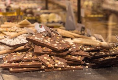 Tablettes de chocolat au lait et noir garnies de noisettes et de fruits confits, empilées dans la vitrine d'un chocolatier