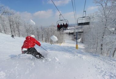 Skieur en anorak rouge sur une piste enneigée de Liberty Mountain, sous les arbres givrés, avec un télésiège en arrière-plan