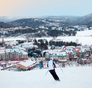 Mont-Tremblant, Canada - February 9, 2014: Skiers and snowboarders are sliding down the main slope at Mont-Tremblant. Mont-Tremblant Ski Resort is acknowledged by most industry experts as being the best ski resort in Eastern North America.