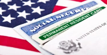 Une carte de résident permanent des États-Unis et une carte de Sécurité sociale posées en éventail sur un drapeau américain