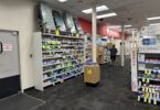 Allée d'un CVS bordée de rayons de médicaments en vente libre, avec l'enseigne rouge de la pharmacie au fond