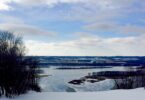 Pente enneigée au sommet de Chestnut Mountain Resort, avec en contrebas le Mississippi gelé, ses îles et les collines de l'Iowa sous un ciel nuageux