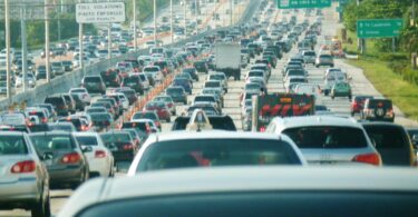 Embouteillage sur l'autoroute I-95 en direction du nord à Miami : des centaines de voitures sur plusieurs voies, sous des panneaux verts de sortie