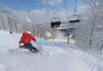 Skieur en anorak rouge sur une piste enneigée de Liberty Mountain, sous les arbres givrés, avec un télésiège en arrière-plan