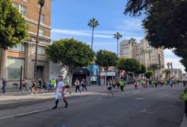 Des dizaines de coureurs, beaucoup en tee-shirts jaune fluo, remontent Hollywood Boulevard sous un ciel bleu, entre palmiers et immeubles anciens, avec au loin l'enseigne verticale du théâtre Pantages
