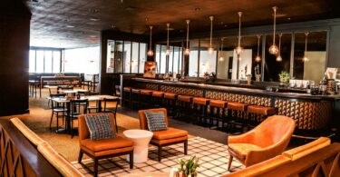 Salle de restaurant-bar avec fauteuils, grand comptoir et suspensions