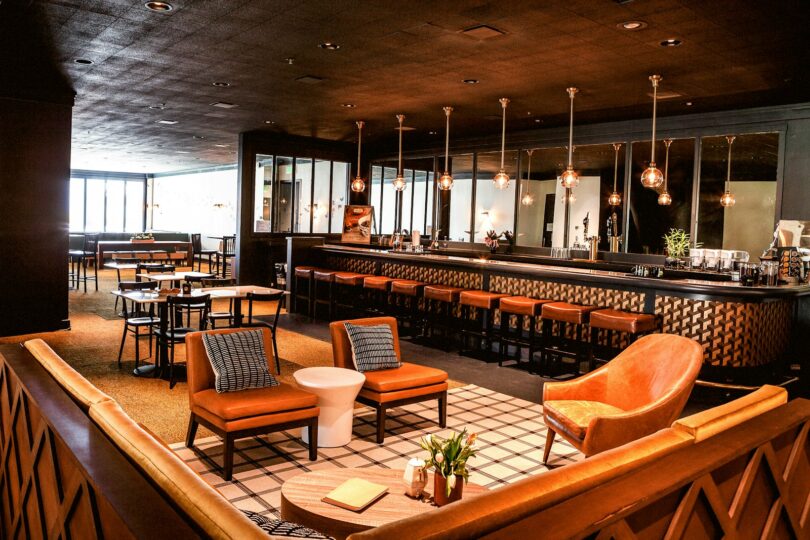 Salle de restaurant-bar avec fauteuils, grand comptoir et suspensions