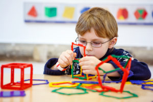 Little kid boy building geometric figures with plastic blocks